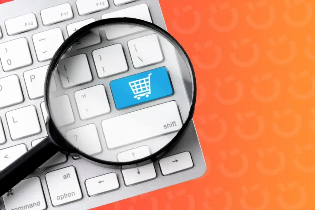 Magnifying glass over a blue shopping cart key on a keyboard, symbolizing online shopping search.